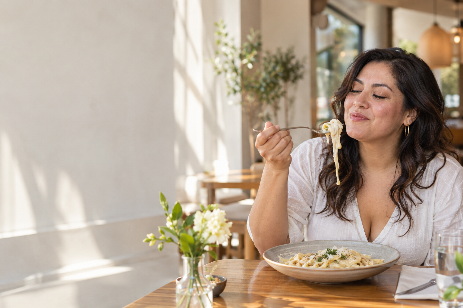 Mujer disfrutando una pasta cremosa con queso